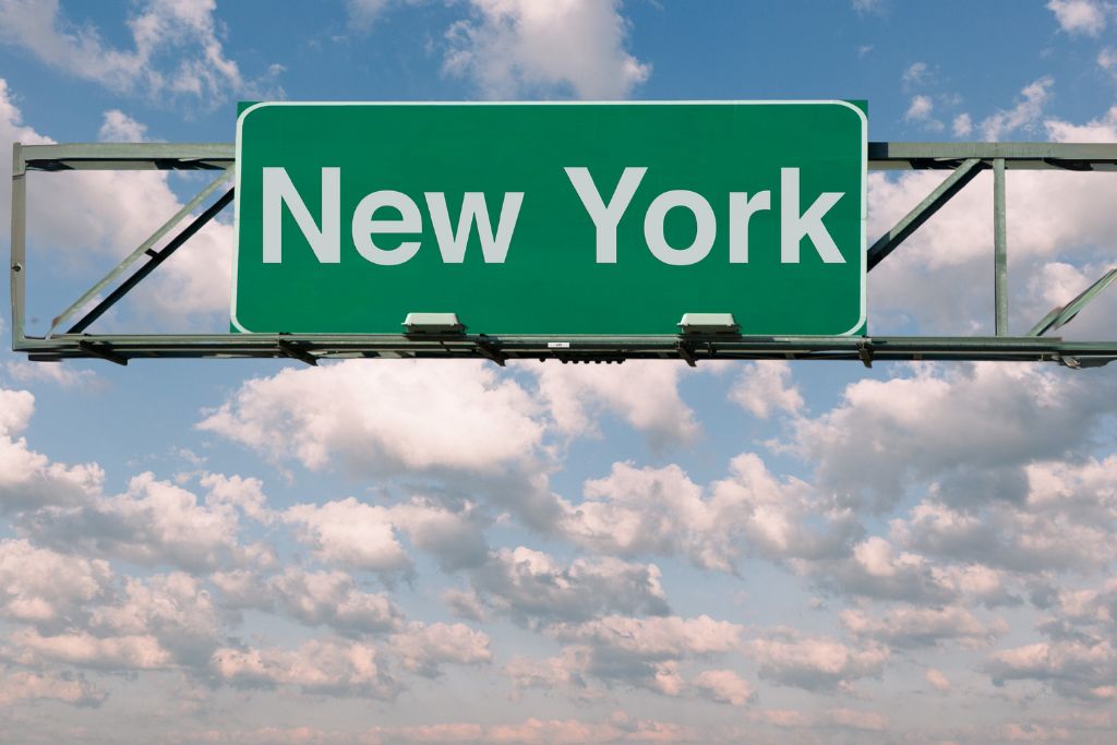 new york on green road sign with sky background