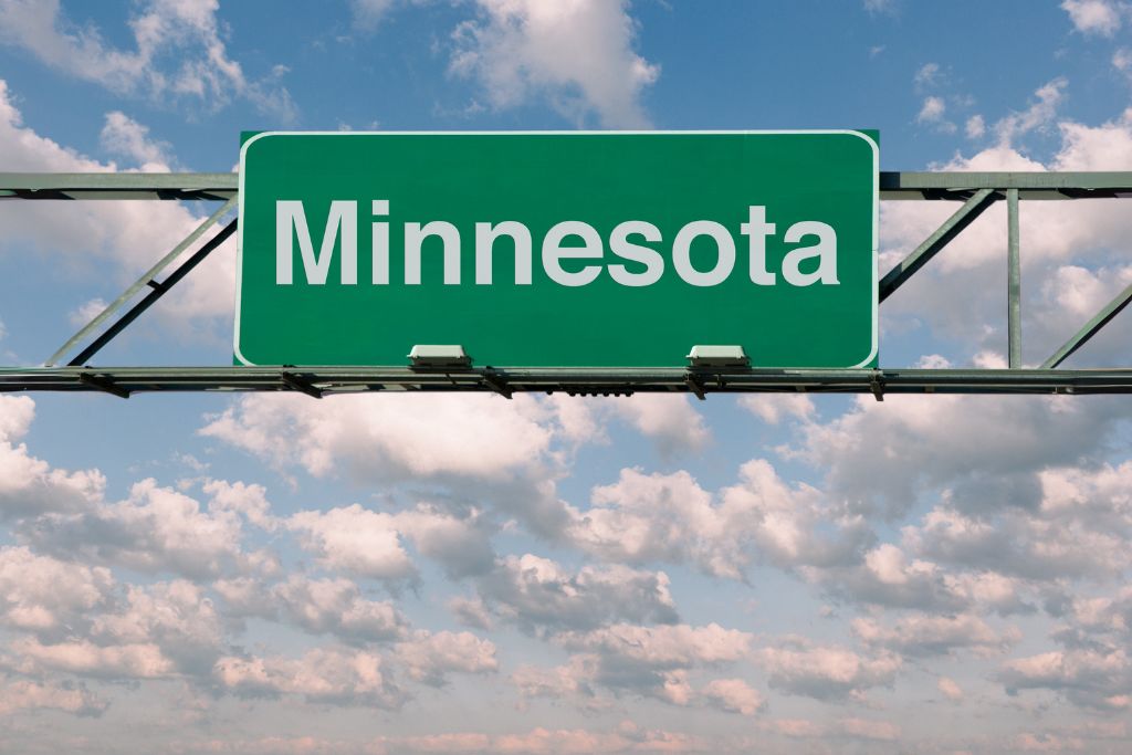 minnesota on green road sign with sky background
