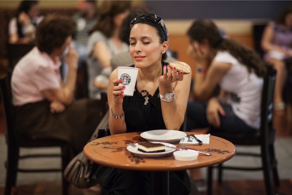 woman holding a cup of starbucks coffee and cookie
