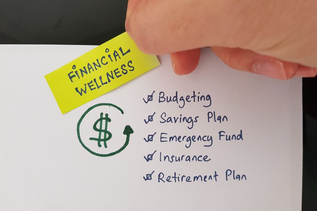 holding a yellow paper showing financial wellness text