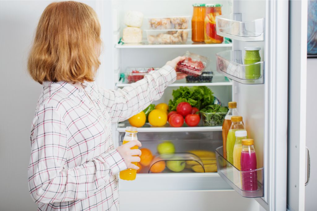 young girl at fridge filled with foods