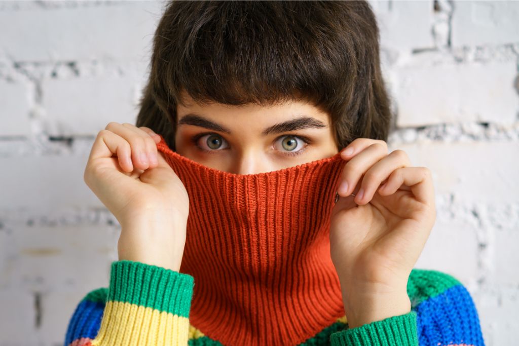 young woman covering her face with a sweater