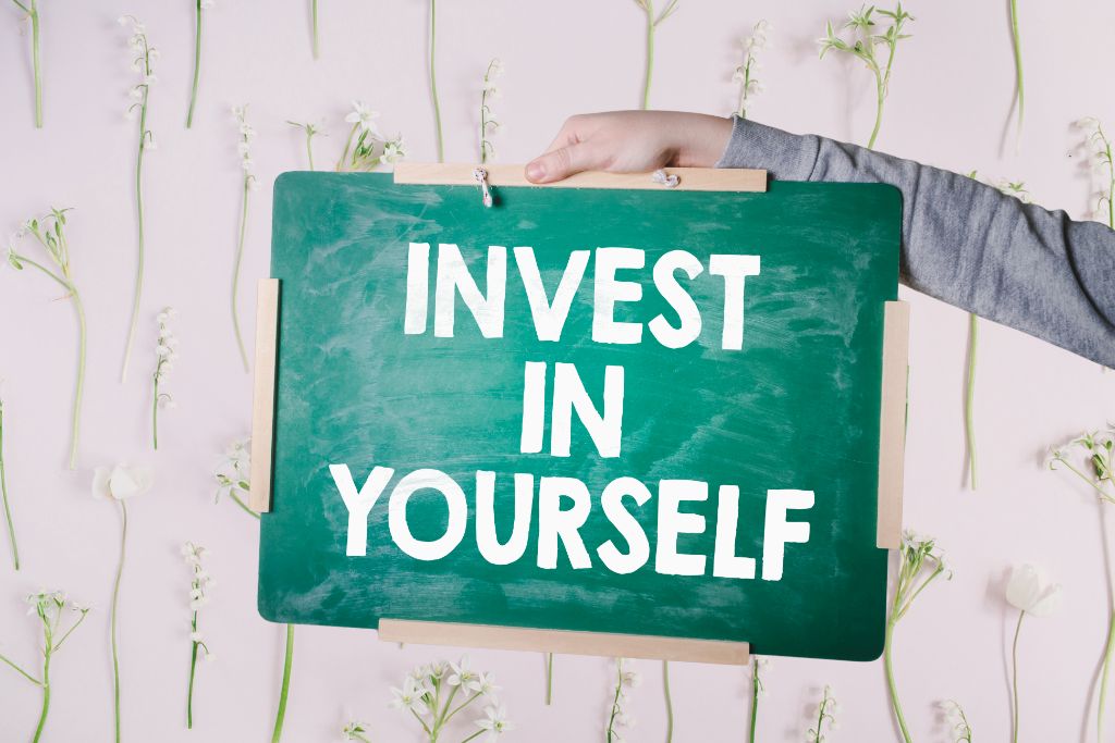 person holding a board with invest in yourself text