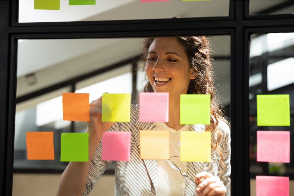 woman writes task list on sticky notes